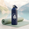 Botella térmica reutilizable azul sobre esterilla de yoga, ideal para deporte y bienestar