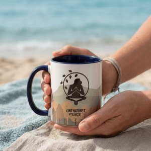 Taza con diseño de meditación y naturaleza sostenida en la playa frente al mar